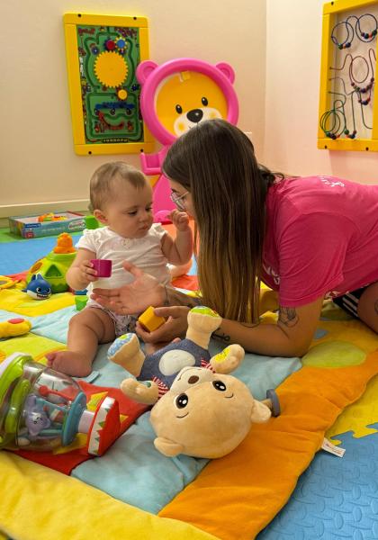 Bambina gioca con una donna su un tappeto colorato.