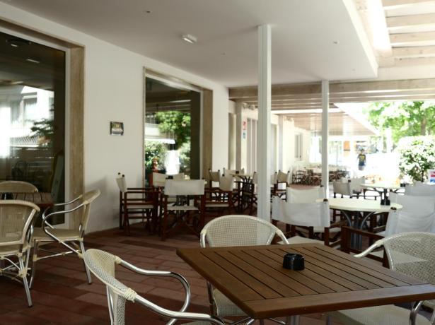 Terrazza con tavoli e sedie, ambiente tranquillo e luminoso.