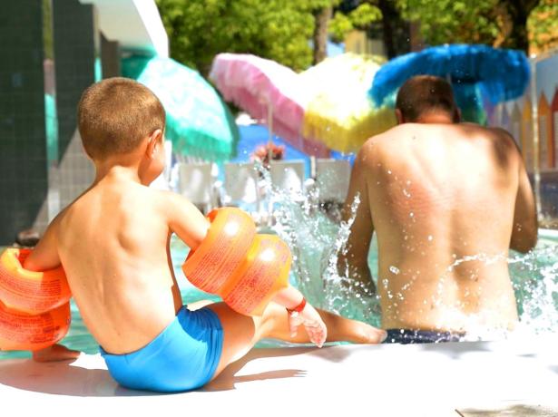 Bambino e adulto giocano in piscina con salvagente.