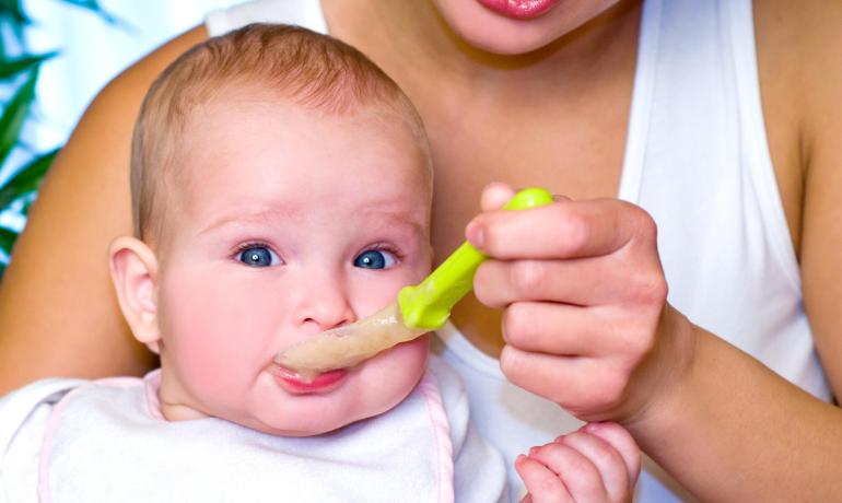 Mamma dà pappa al bambino con cucchiaio.