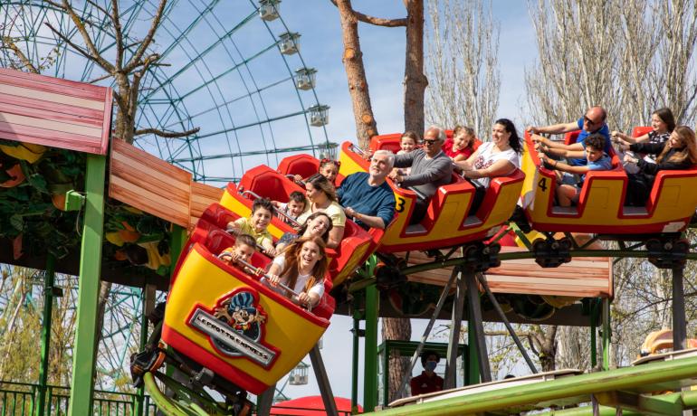 Colorful roller coaster with smiling, excited, and happy people.