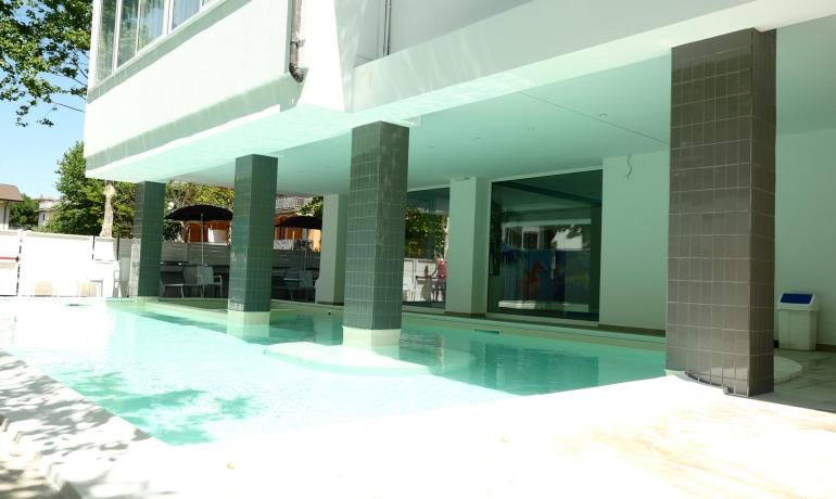 Piscina luminosa sotto un portico, atmosfera rilassante e moderna.