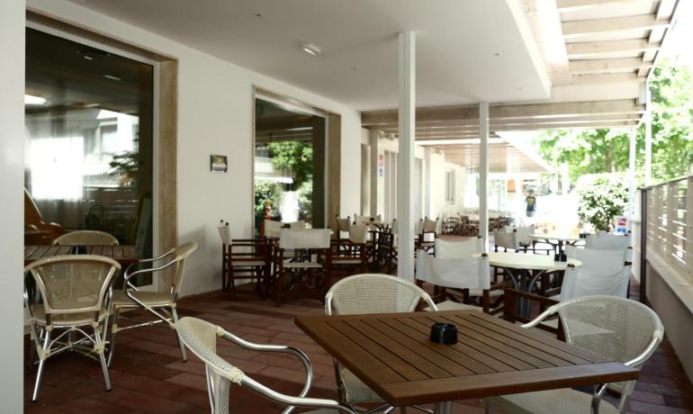 Terrace with tables and chairs, peaceful and bright environment.