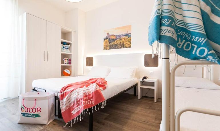 Camera luminosa con letto matrimoniale e letti a castello, arredamento moderno.