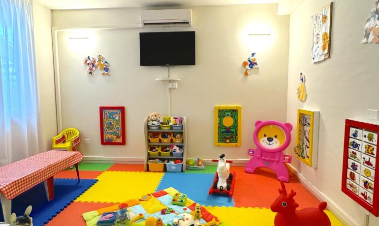 Colorful playroom with mats, toys, and wall decorations.