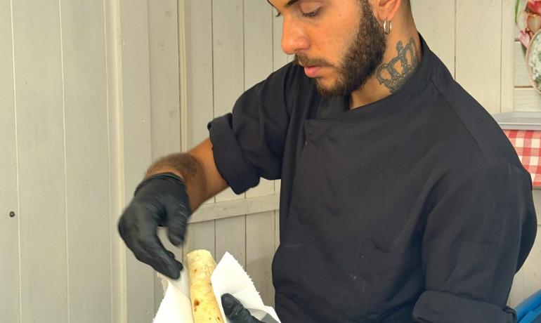 Chef carefully prepares flatbread in kitchen.