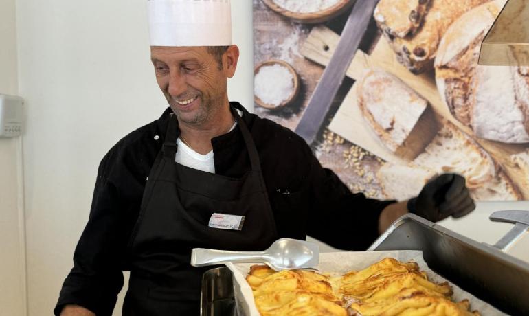 Chef with hat serves freshly baked pastries.