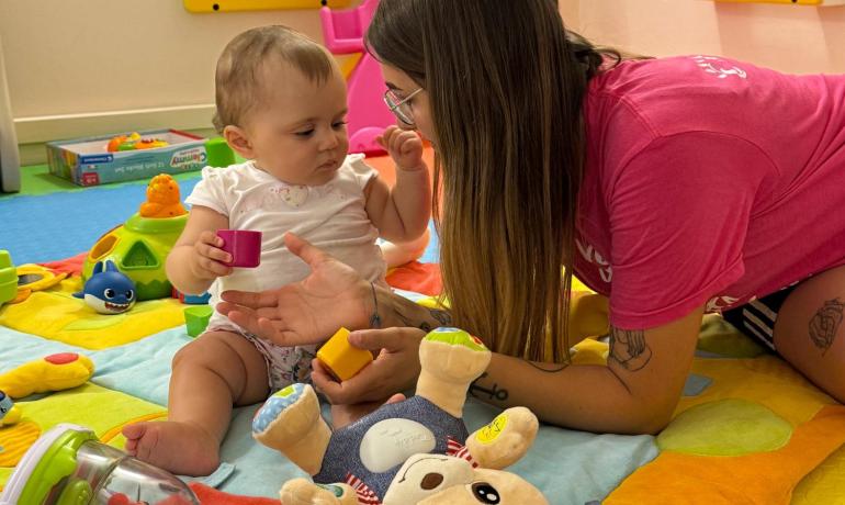 Child plays with a woman on a colorful mat.