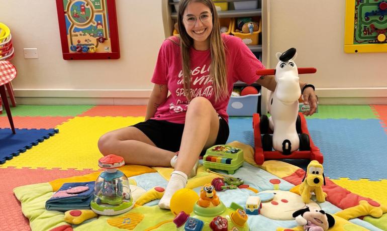 Stanza giochi colorata con giocattoli e persona sorridente.