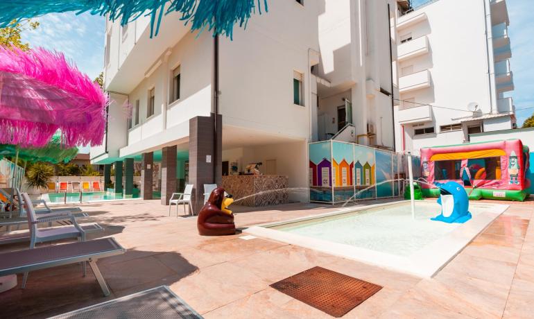 Piscina per bambini con giochi colorati e lettini al sole.