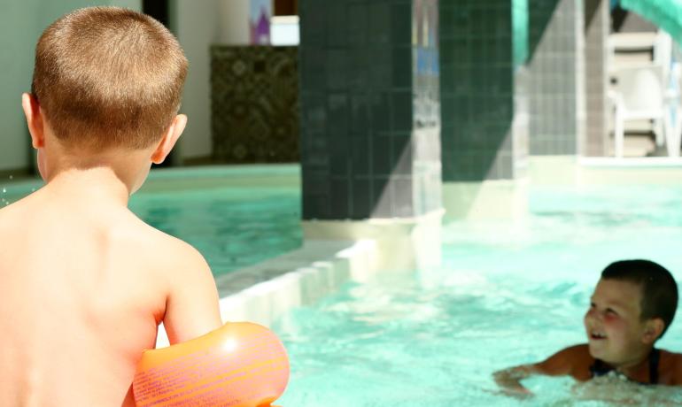 Children playing in a pool with orange floaties.