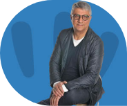 Seated man with glasses, blue background.