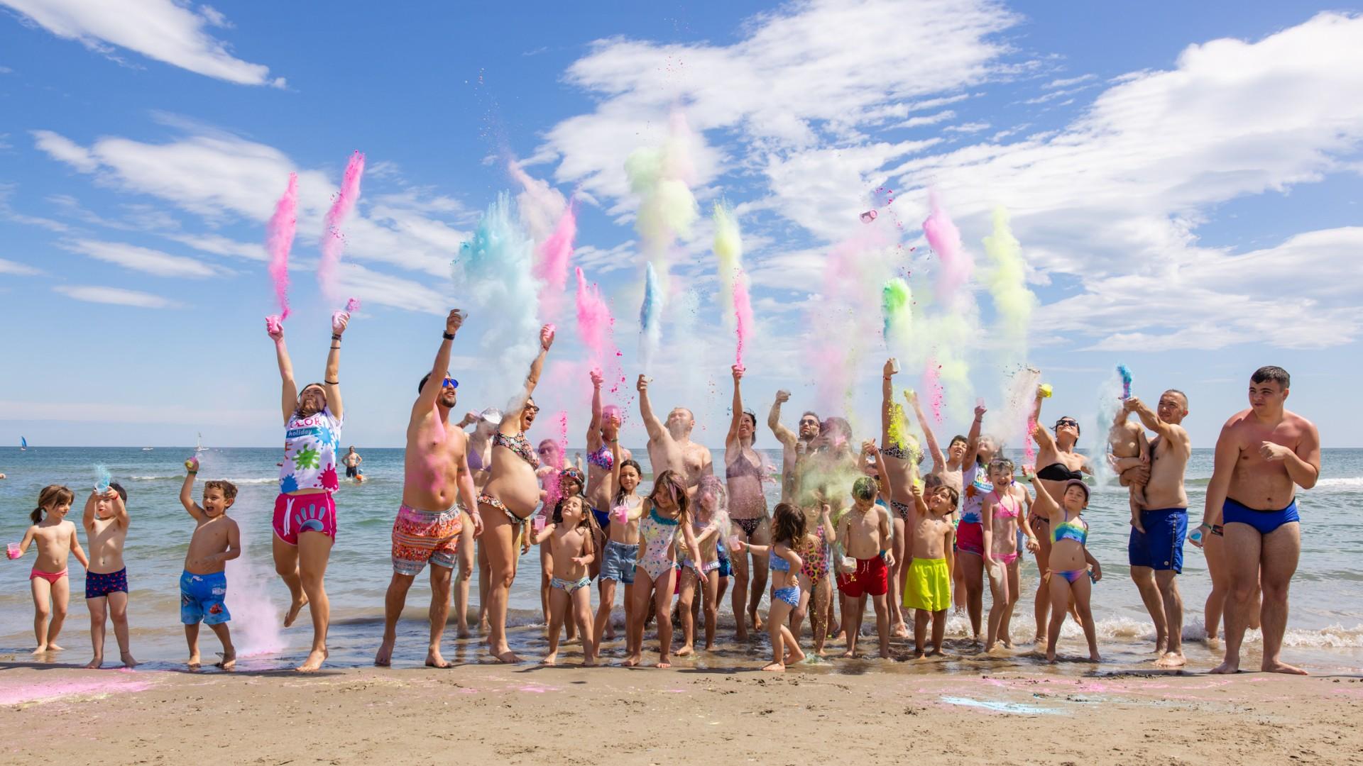 People throw colored powders on the beach on a sunny day.
