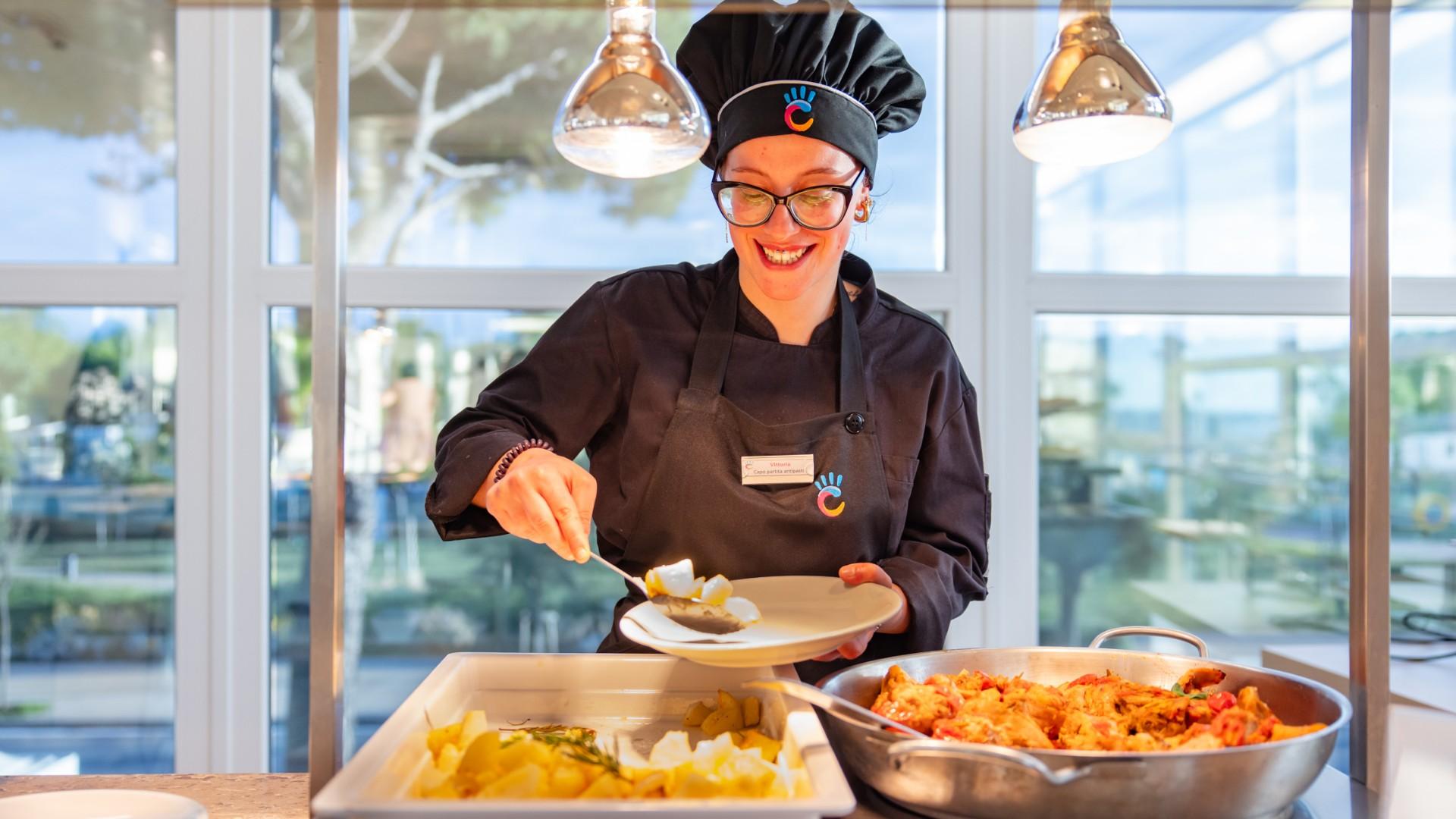 Smiling chef serves food in a bright restaurant.