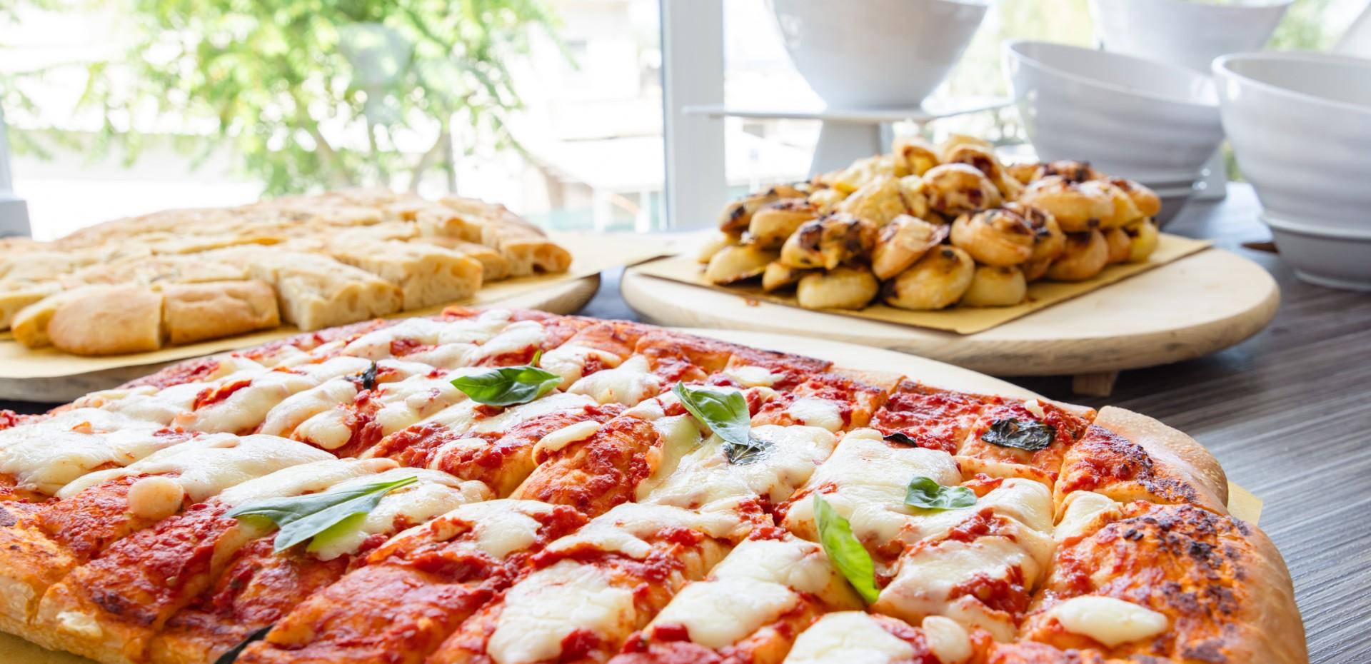 Margherita pizza with basil and bread in the background.
