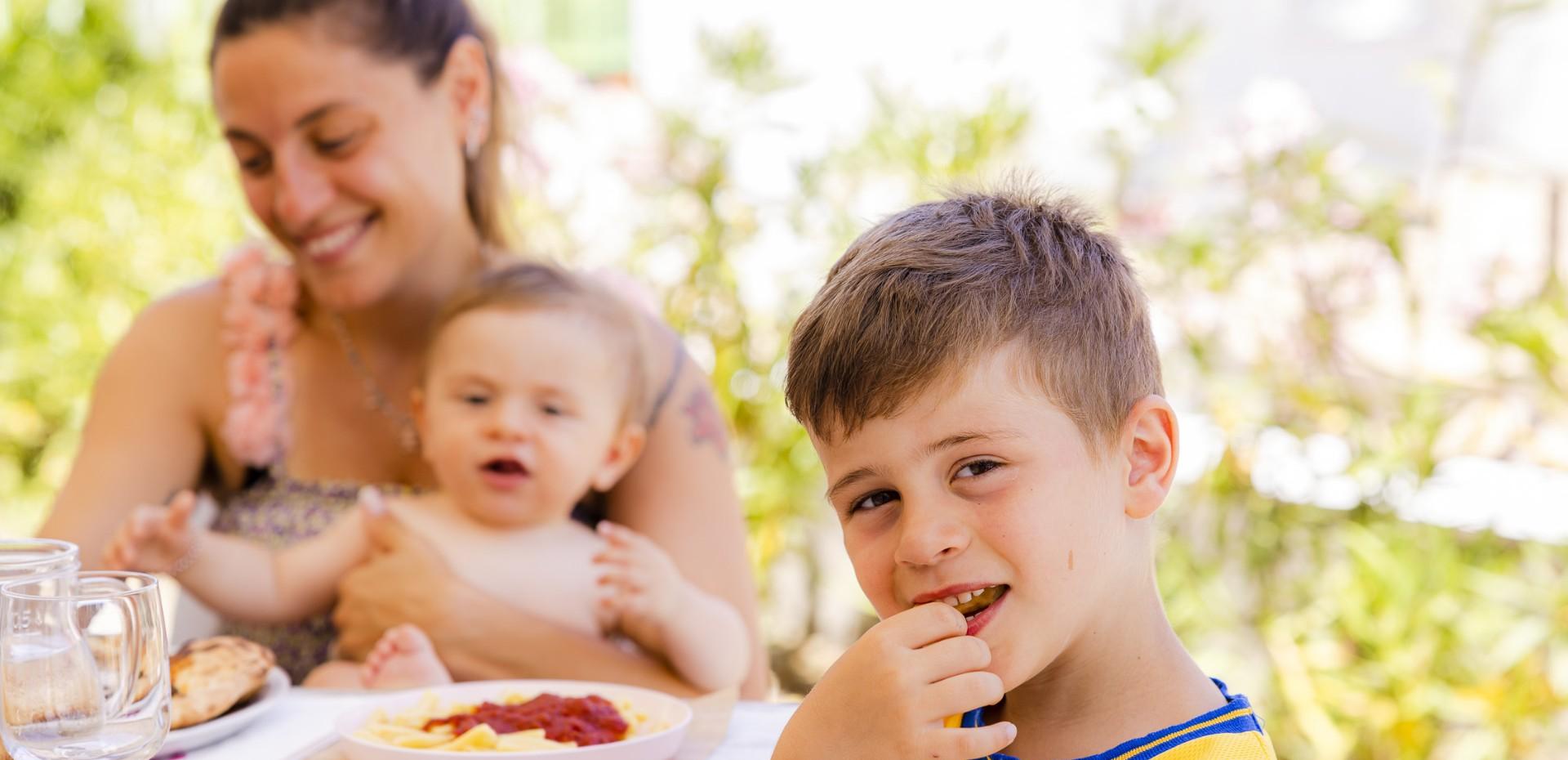 Happy family eating together outdoors on a sunny day.