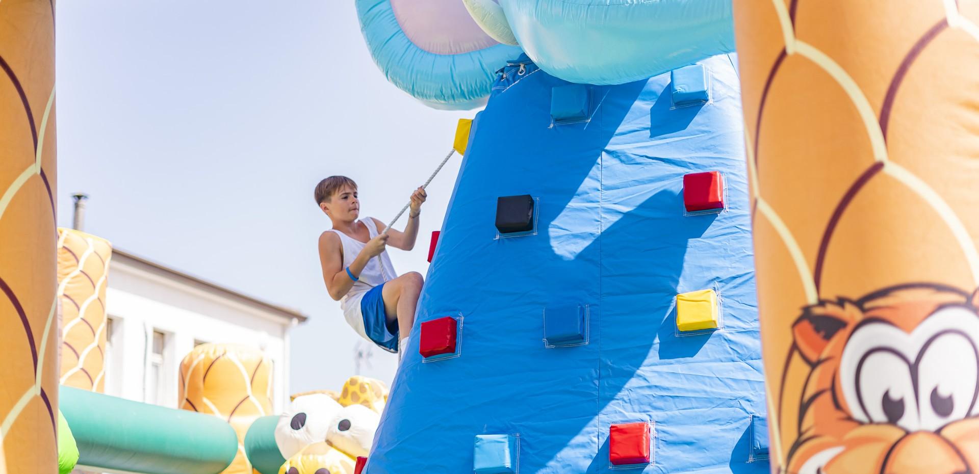 Child climbing colorful inflatable wall at a playground.