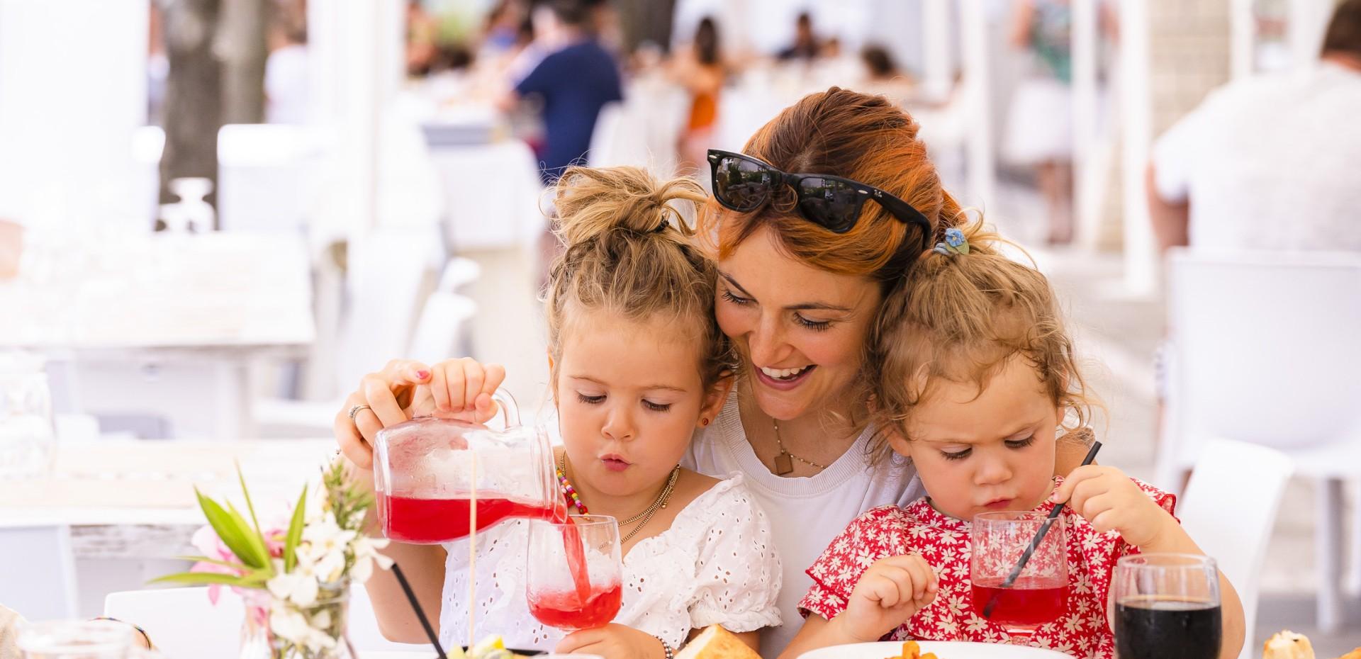 Mother and daughters smile while drinking together at the restaurant.