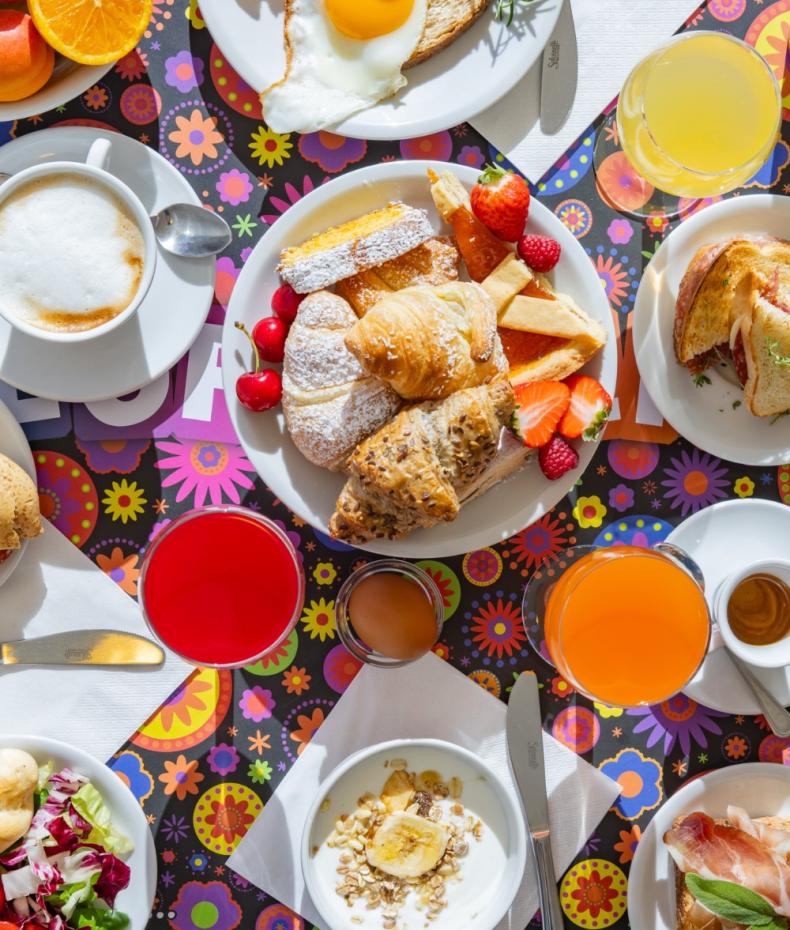 Colorful breakfast with pastries, fruit, eggs, and drinks.