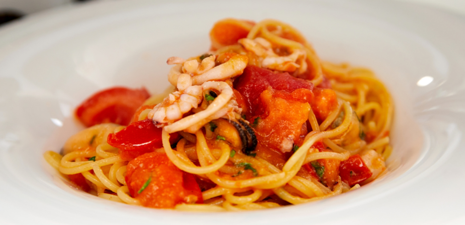 Spaghetti ai frutti di mare con pomodori freschi e calamari.