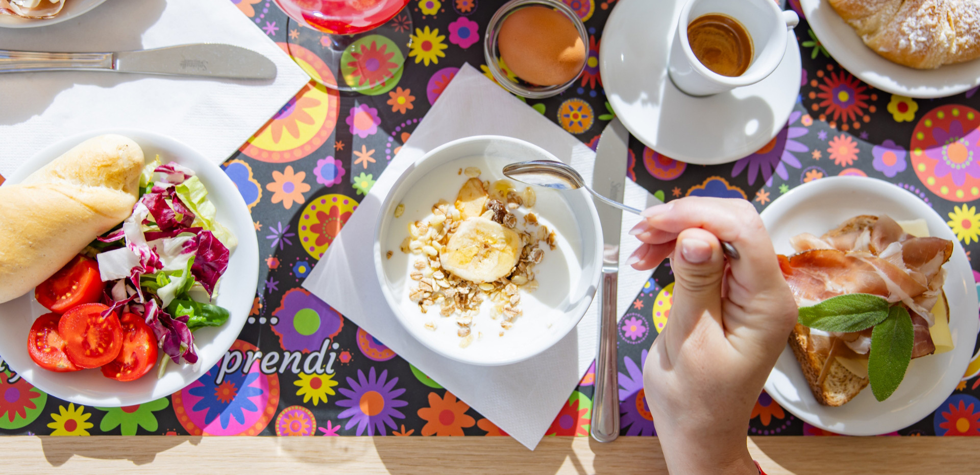 Colazione colorata con yogurt, frutta, insalata, caffè e pane con affettati.