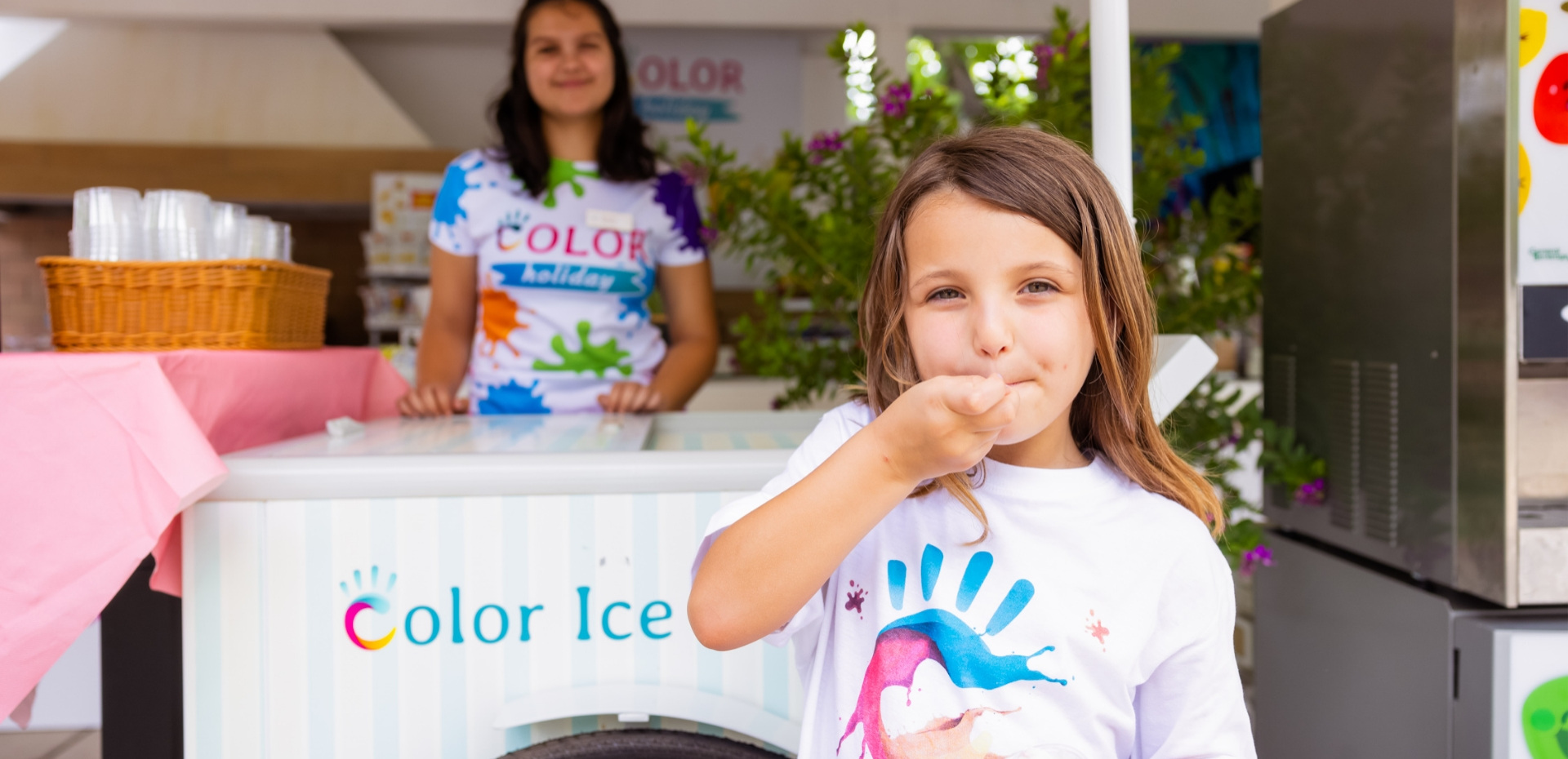 Happy child enjoys ice cream, colorful background and smiling vendor.