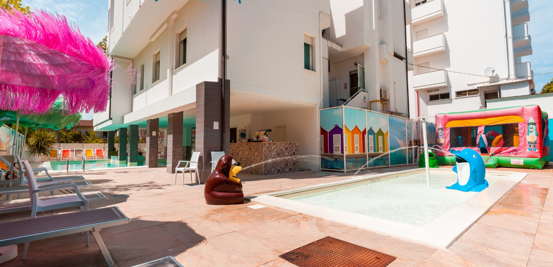 Piscina con giochi acquatici e gonfiabili colorati in un ambiente soleggiato.