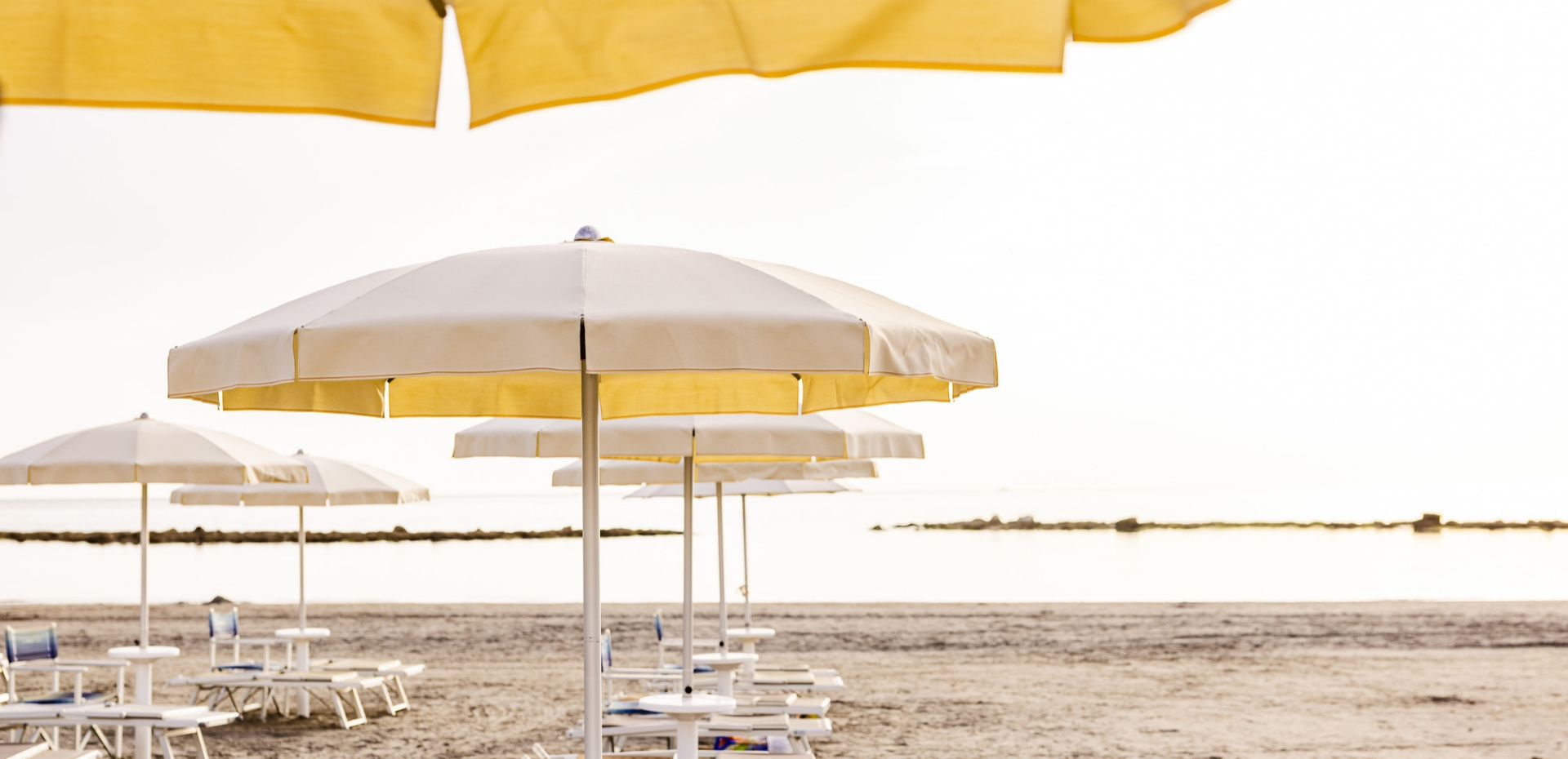 Ombrelloni bianchi e gialli su una spiaggia tranquilla al tramonto.