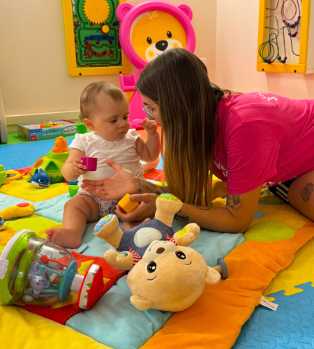 Bambina e donna giocano felici su un tappeto colorato, circondati da giocattoli vivaci.