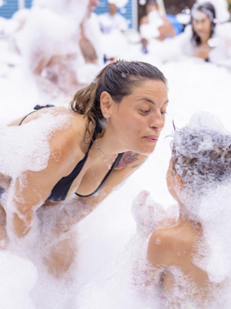 Persone si divertono in una festa di schiuma, immerse in bolle e sorrisi.