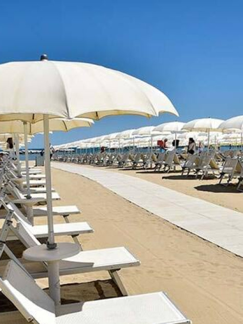 Sunny beach with white umbrellas, relaxing atmosphere, and blue sky.