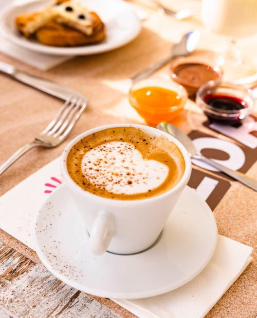 Colazione con croissant, pane tostato, dolci, yogurt e bevande su un tavolo.