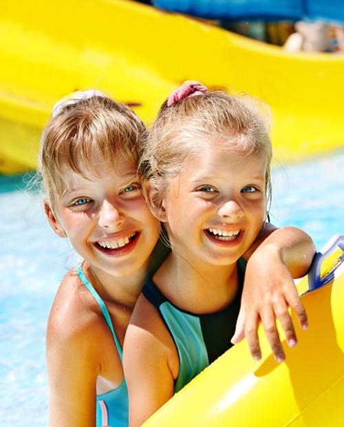 Due bambine sorridenti in piscina con un gonfiabile colorato.