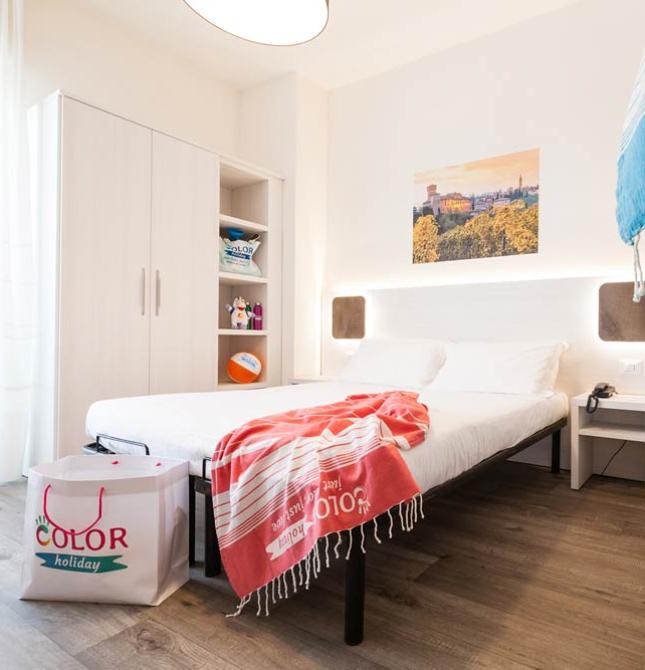 Camera moderna con letto matrimoniale, arredamento essenziale e dettagli colorati.