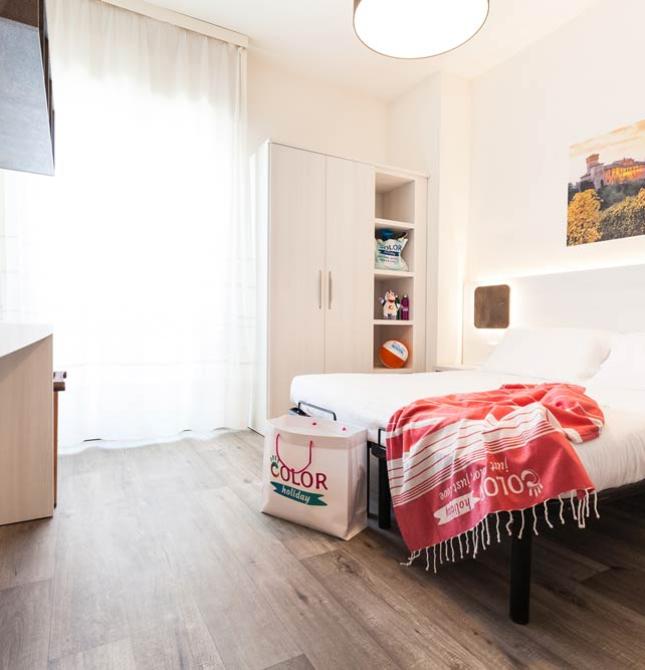 Camera moderna con letto matrimoniale, armadio e decorazioni colorate.