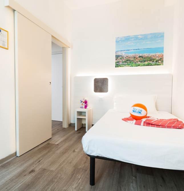 Camera moderna con letto singolo, pavimento in legno e decorazioni colorate.
