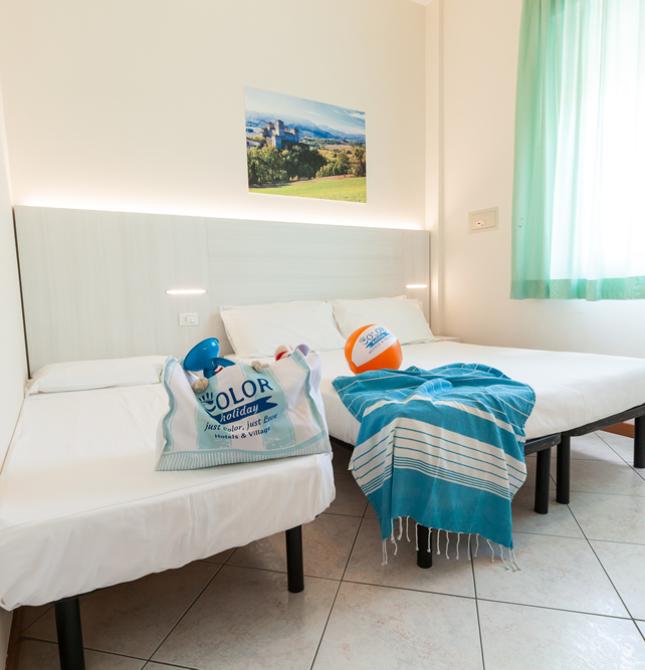 Camera luminosa con due letti, decorata con accessori da spiaggia e foto paesaggistica.