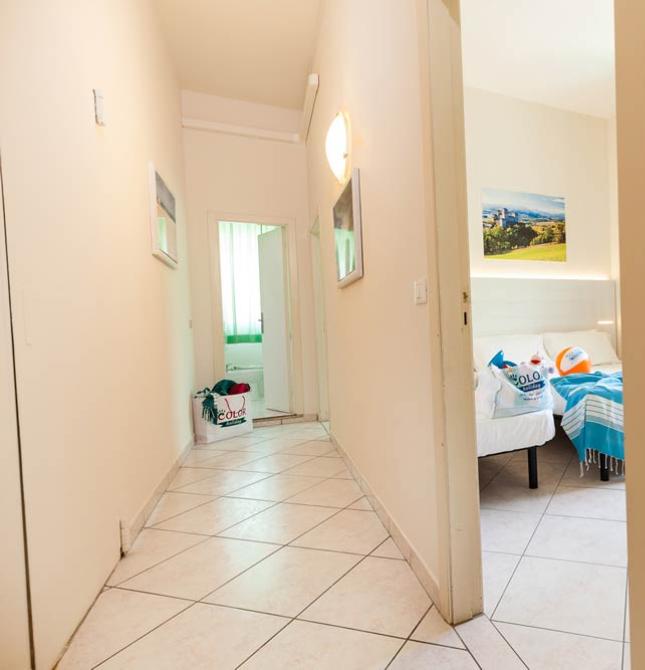 Corridoio luminoso con accesso a camera da letto e bagno, arredamento semplice e moderno.