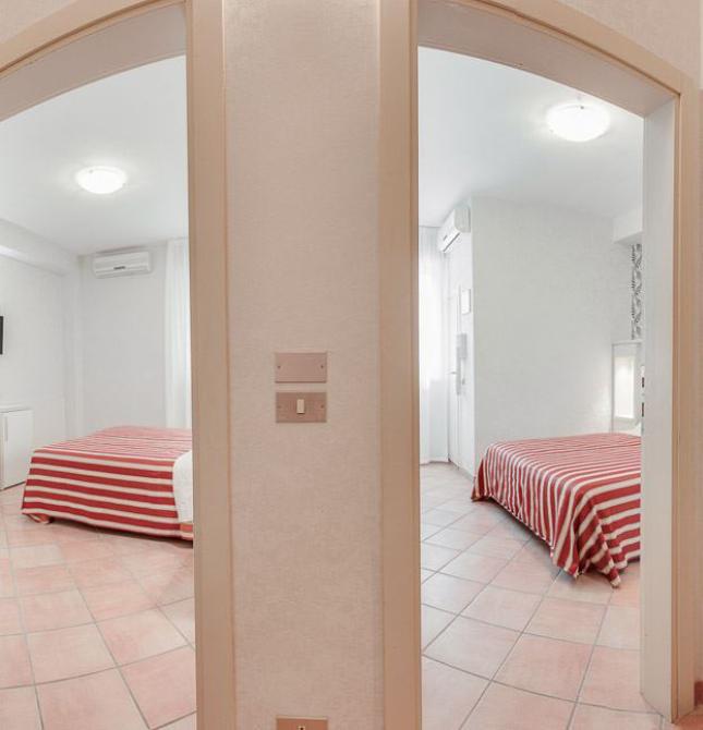 Due camere da letto con copriletto a righe rosse e pavimento in piastrelle.